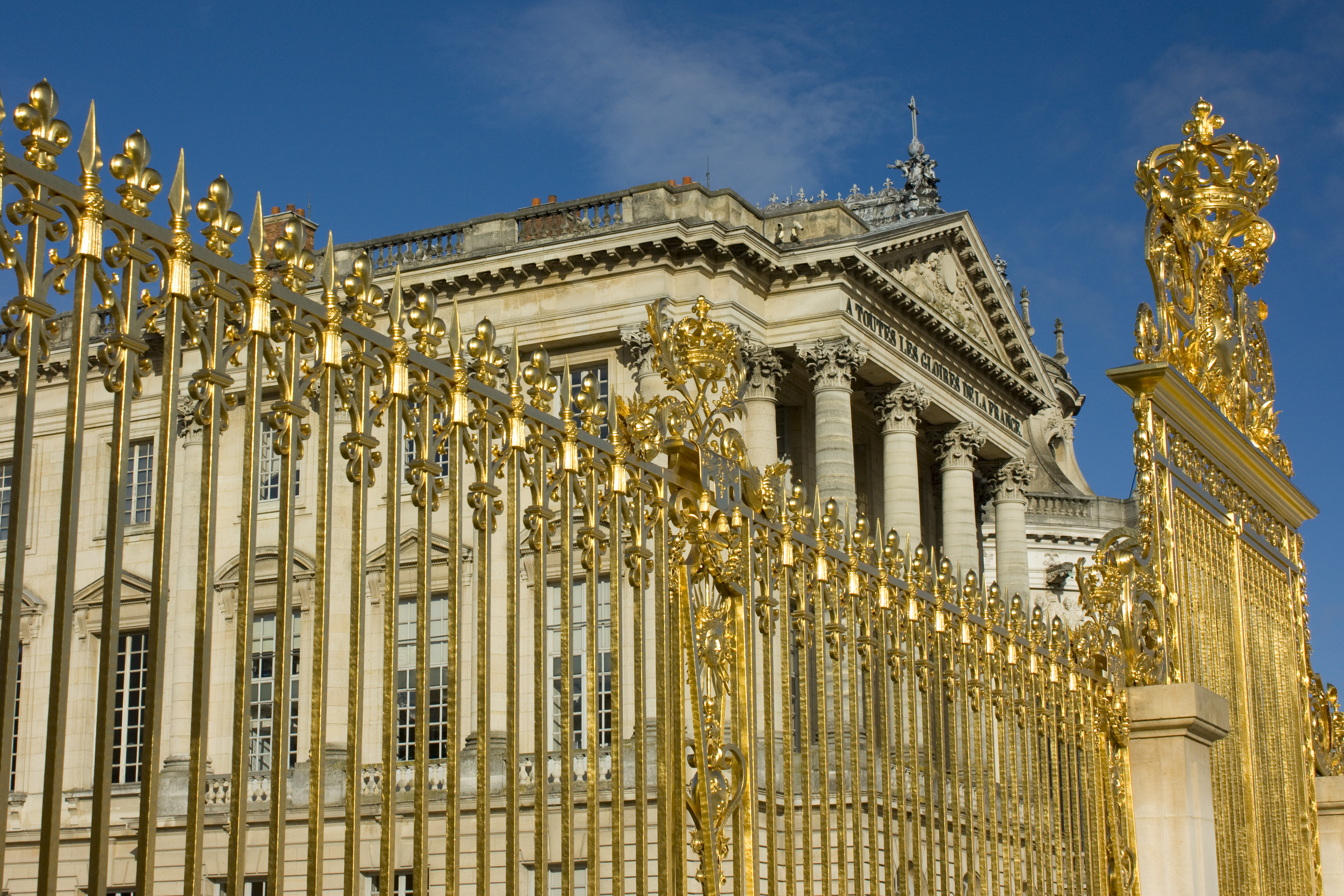 Fragment of golden entrance gates to the Versailles Palace (Chāteau de Versailles) on a sunny summer day