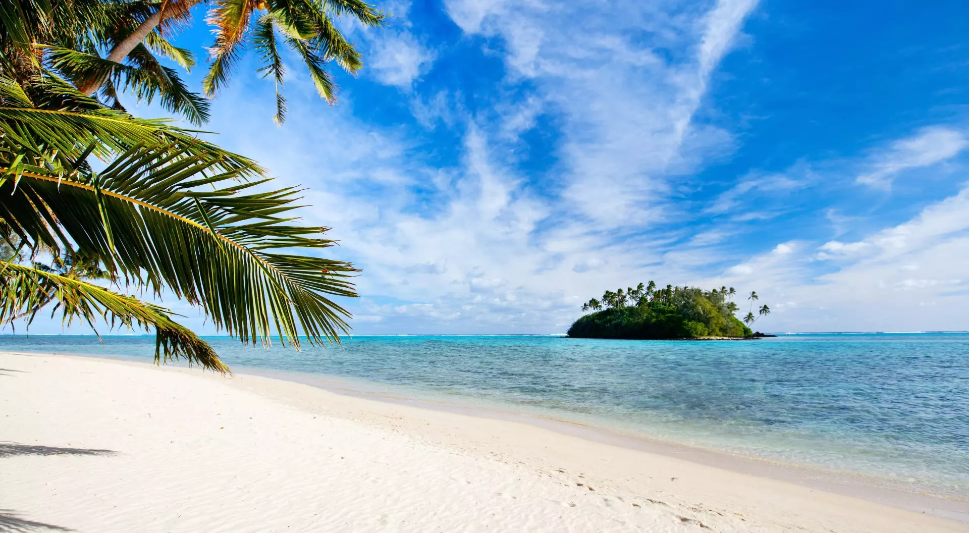 Beautiful tropical beach with palm trees, white sand, turquoise ocean water and blue sky at Cook Islands, South Pacific