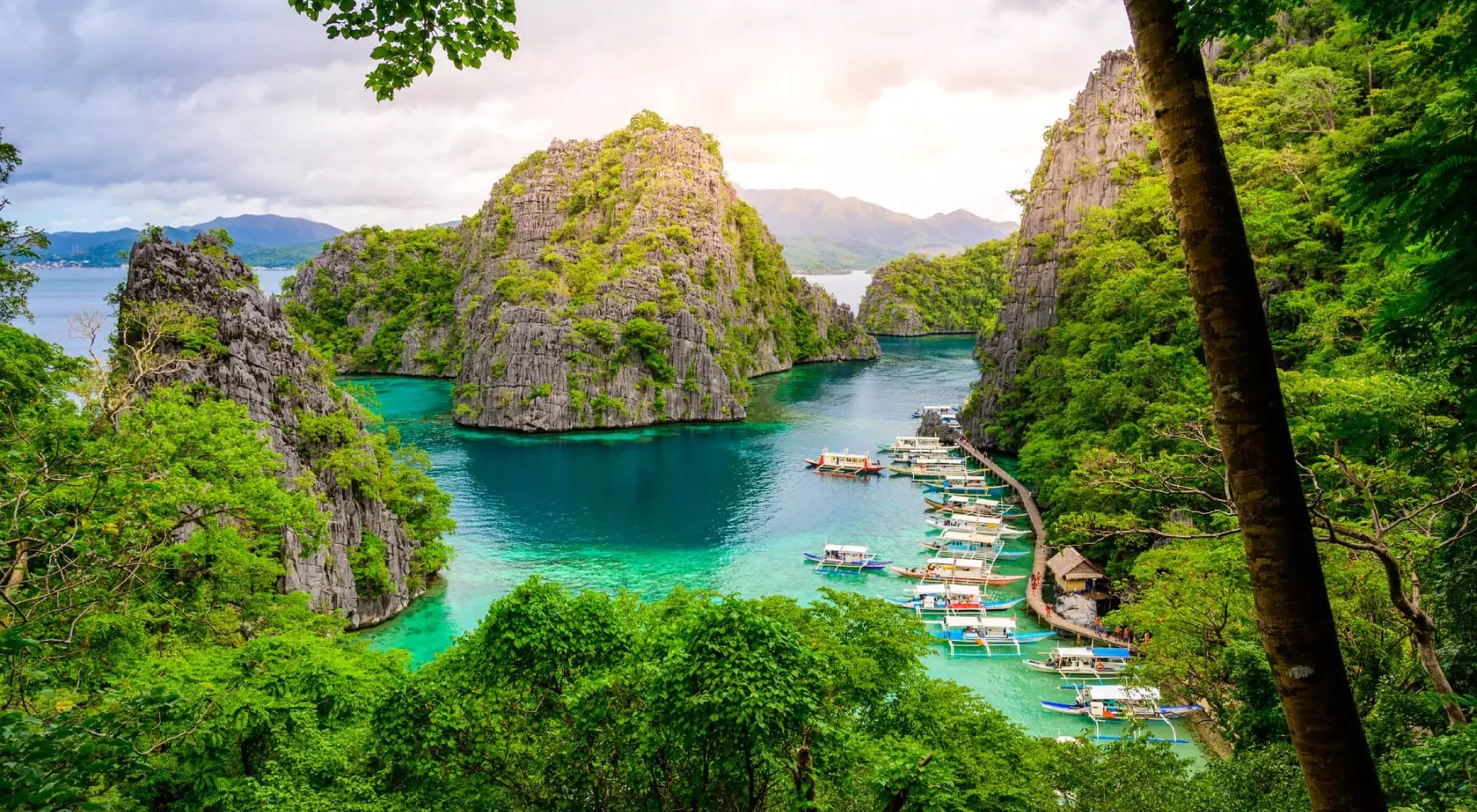 Blue crystal water in paradise Bay with boats on the wooden pier at Kayangan Lake in Coron island, Palawan, Philippines