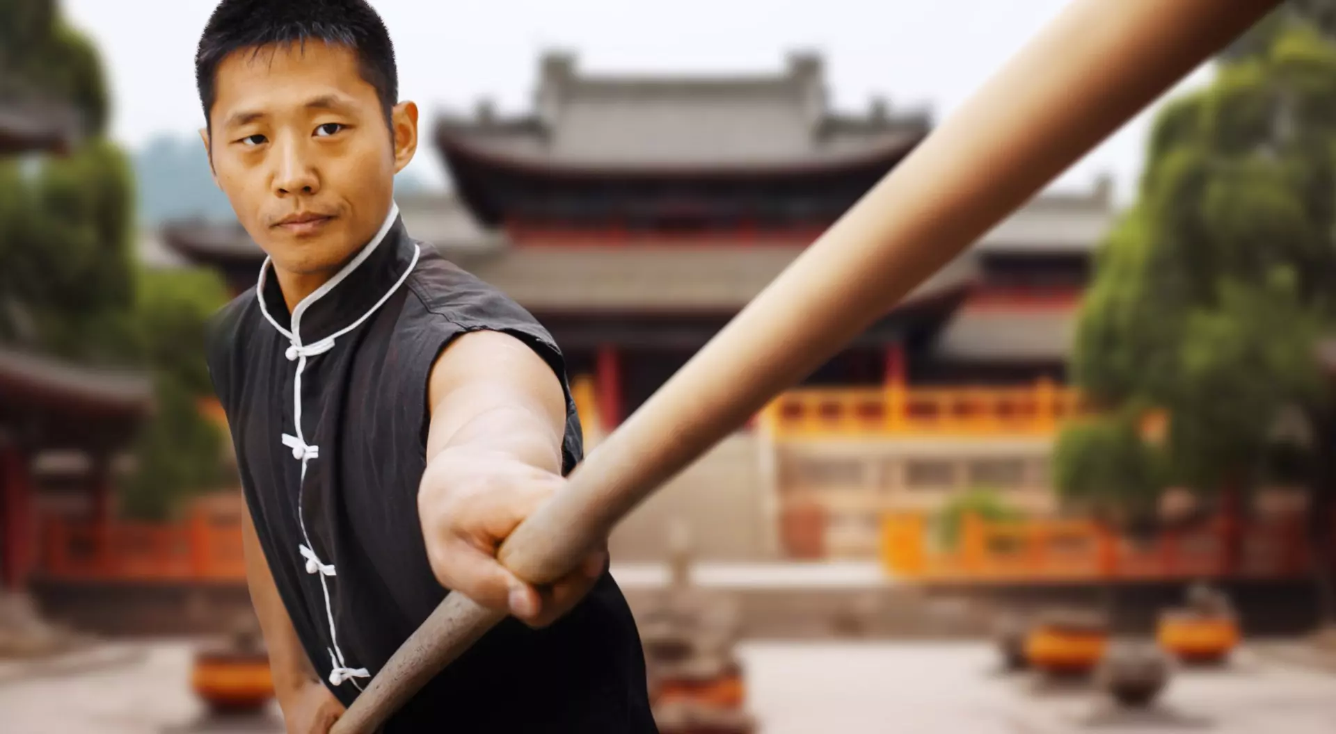 China a man practicing with a martial arts staff in front of a temple