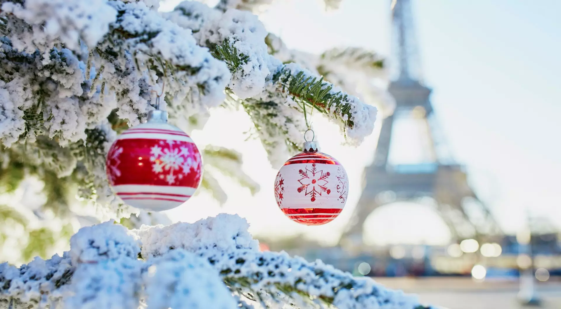 Christmas tree covered with snow and decorated with red toys near the Eiffel tower in Paris, France