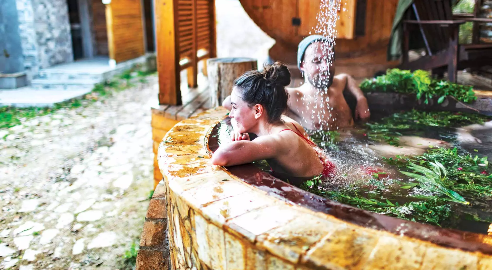 A couple relaxes in an outdoor hot tub at a spa.