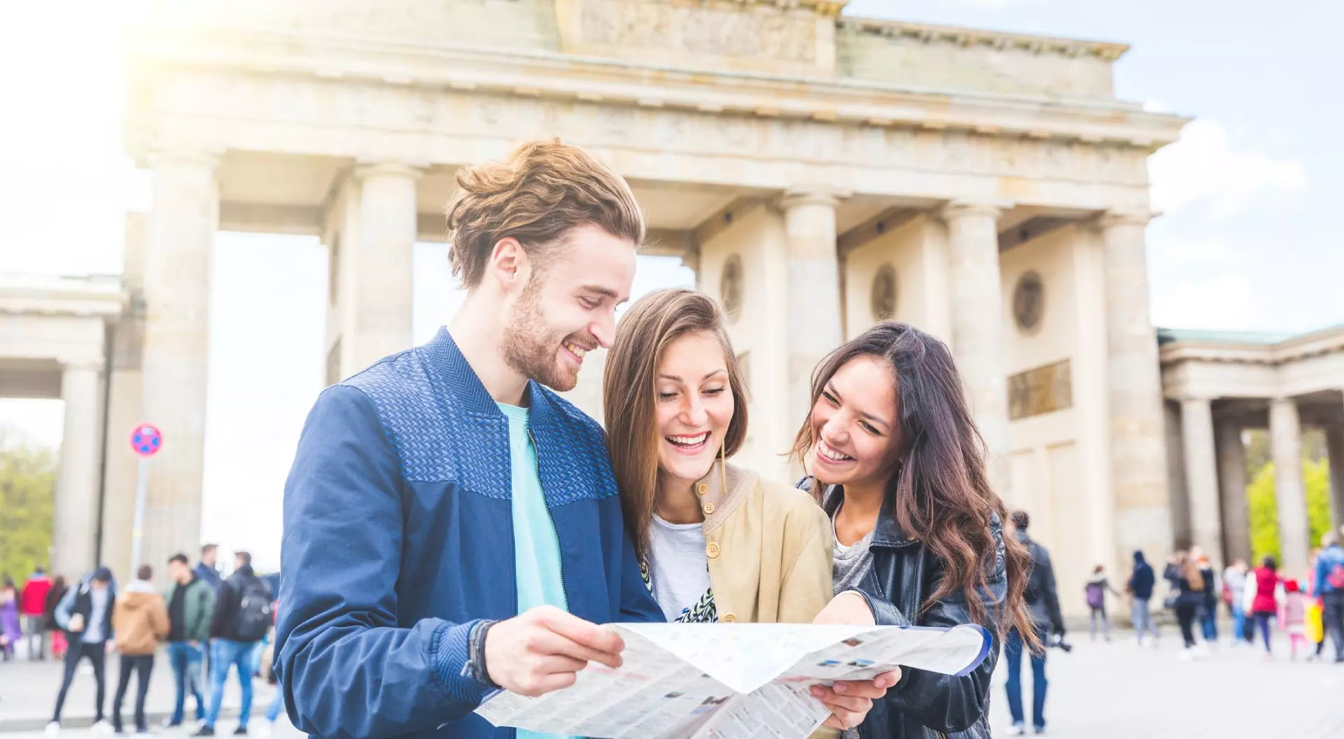 Friends looking at a map with Brandenburg Gate in background, Berlin, Germany