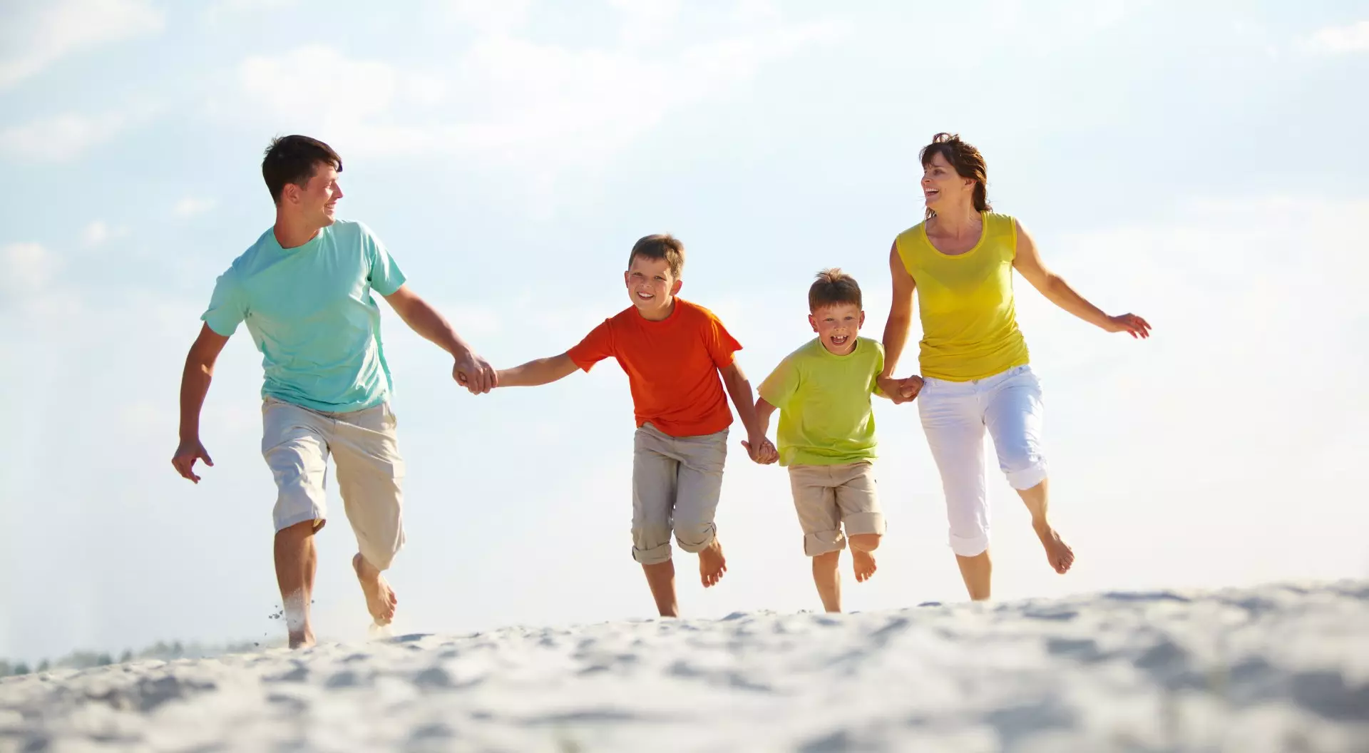 Happy family running down the beach on summer