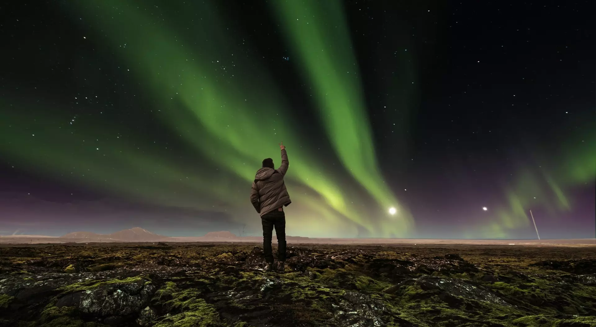 Iceland landscape of amazing beautiful natural phenomenon Aurora Borealis, with a man raising arm , traveling in Iceland