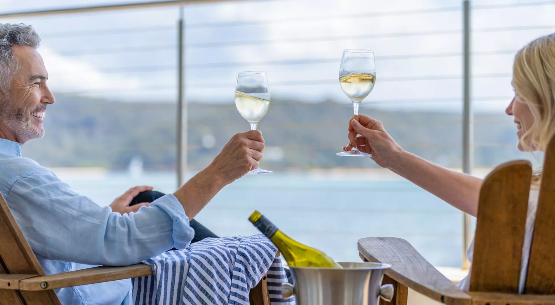 Australia Mature couple drinking wine out on the deck. They are happy and smiling sitting in deck chairs.