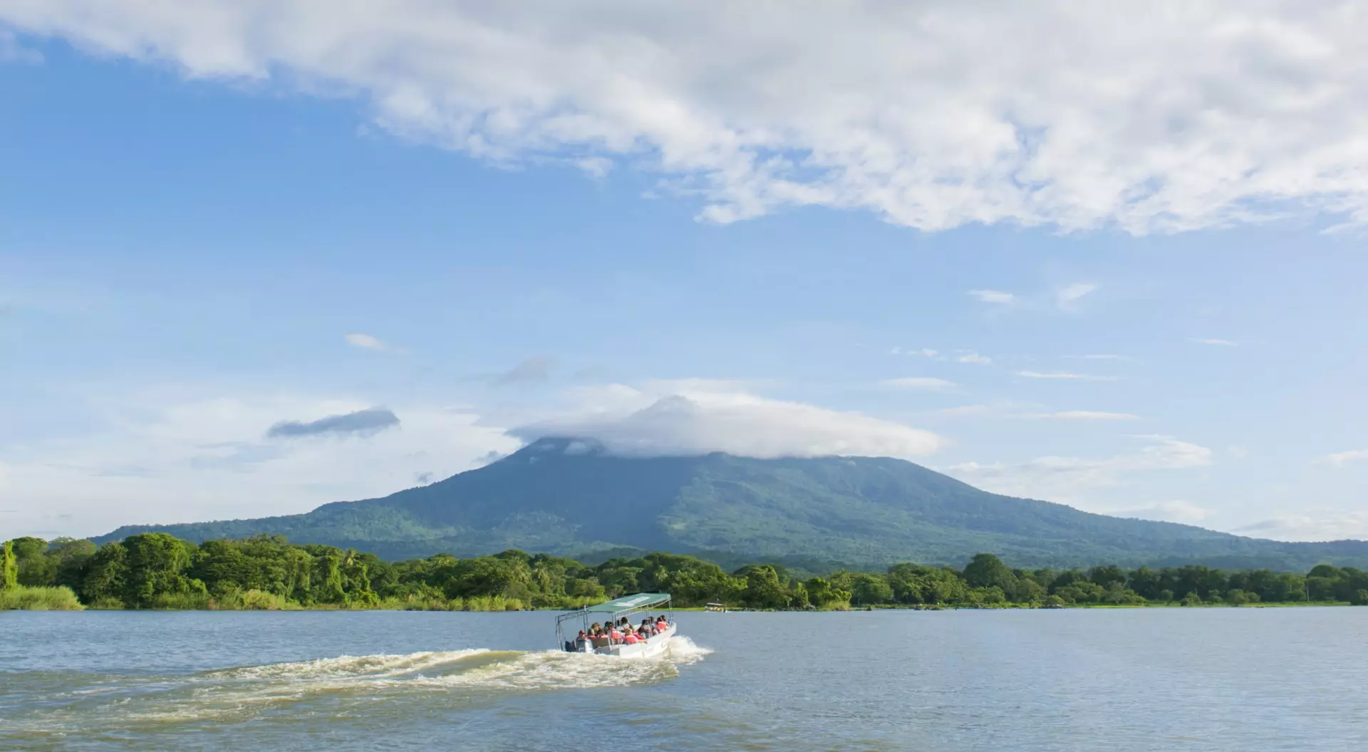 Volcan Mombacho, Nicaragua (©Visit Nicaragua) A boat races across a lake in front of Volcan Mombacho in Nicaragua.