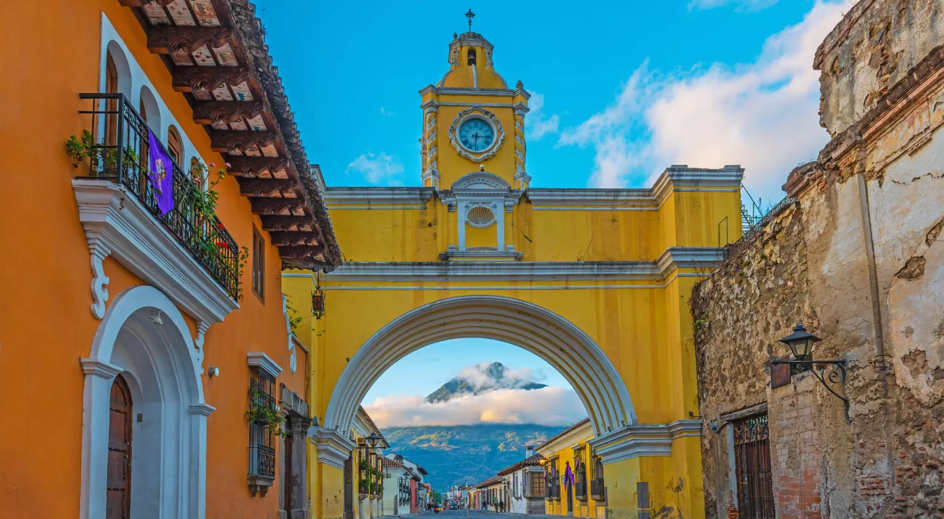 Antigua City, Guatemala Colourful yellow arch of Guatemala Antigua city at sunrise with the active Agua volcano in the background, Guatemala