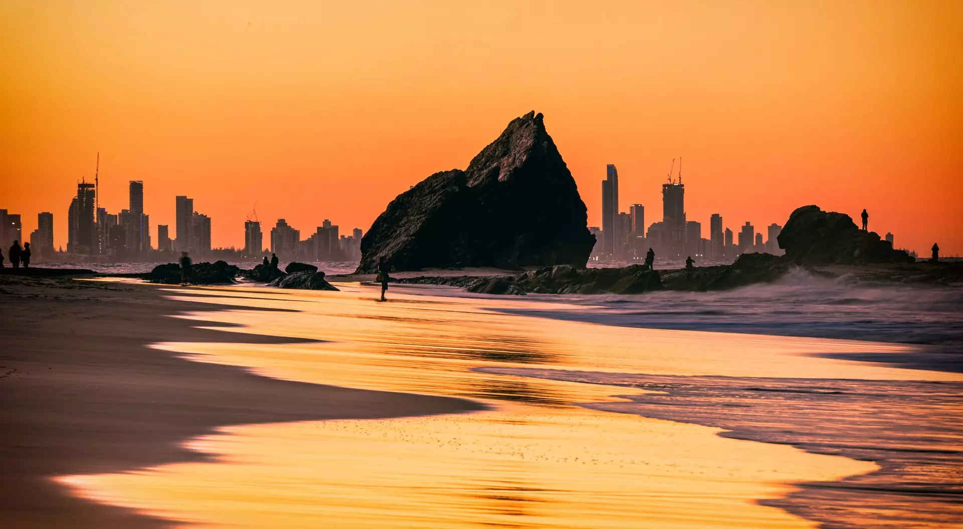 The sunset view of the Currumbin Beach in the twilight and the urban skyline of Gold Coast in the distance