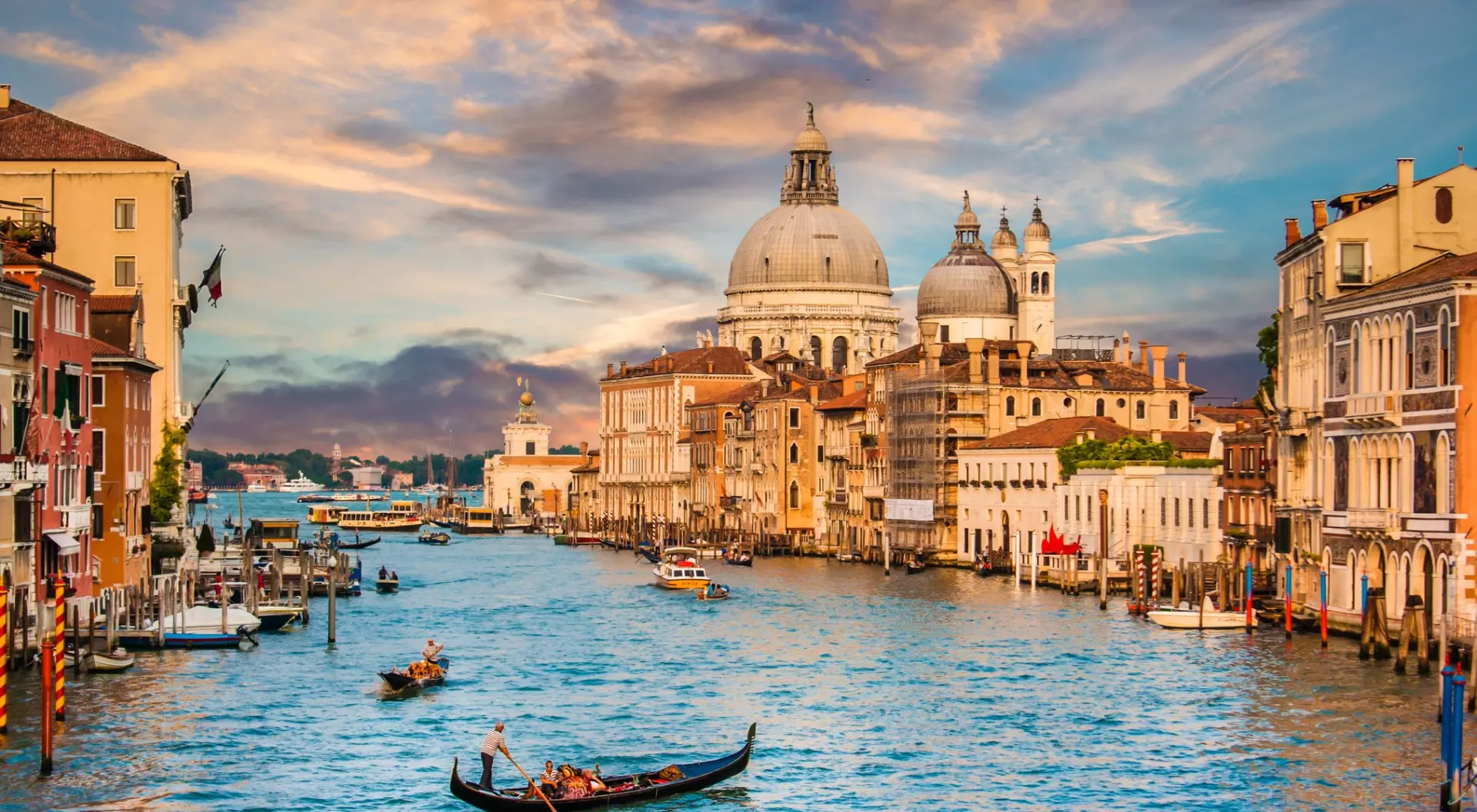 Venice, Italy Traditional Gondola on famous Canal Grande with Basilica di Santa Maria della Salute at sunset in Venice, Italy