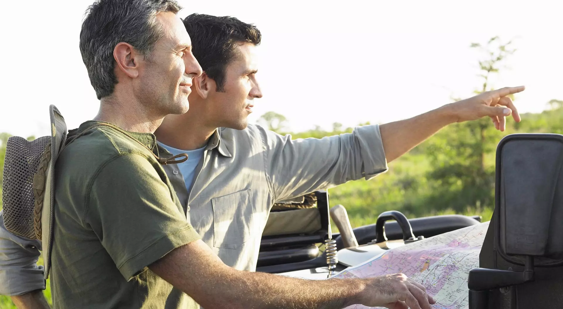 Two male friends with map on bonnet of jeep, Africa