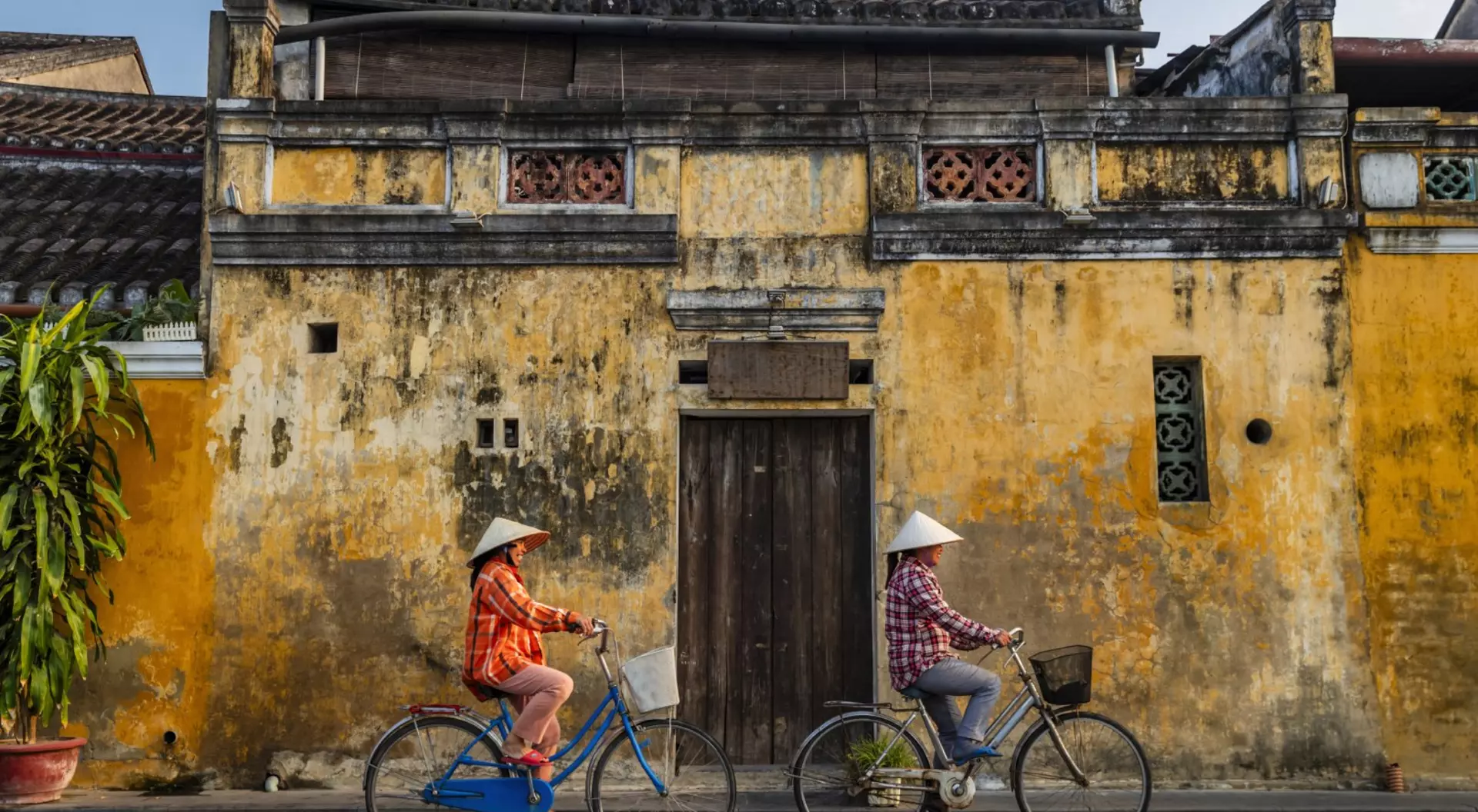 Hoi An, Vietnam Two women riding bicycles wearing traditional Vietnam clothing in the old town of Hoi An in Vietnam