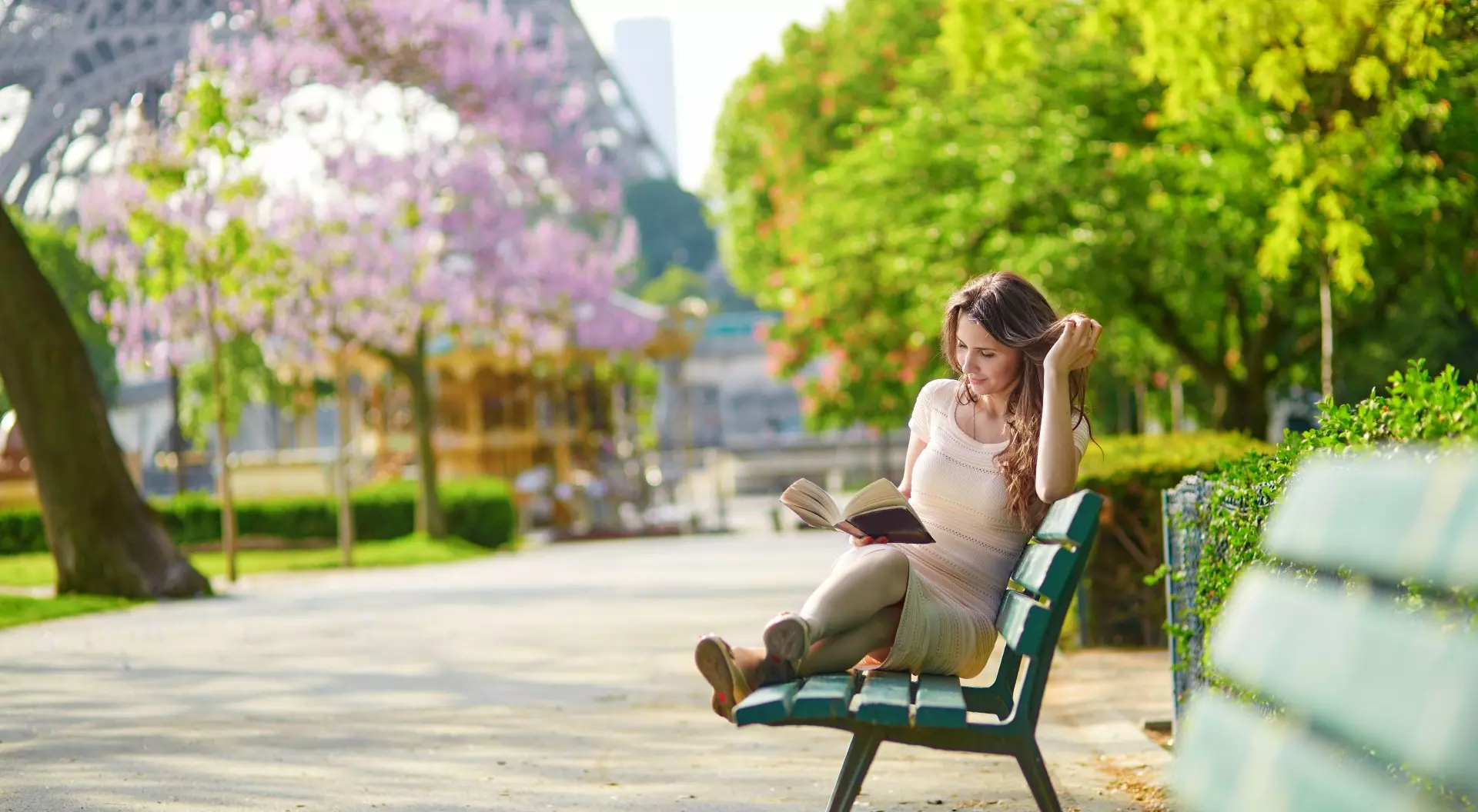 Paris, France Young woman near the Eiffel Tower, reading on a bench, Paris, France