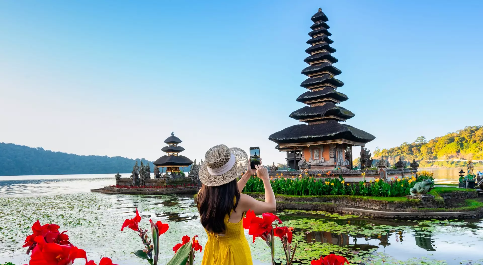 Young woman tourist relaxing and enjoying the beautiful view at Ulun Danu Beratan temple in Bali, Indonesia
