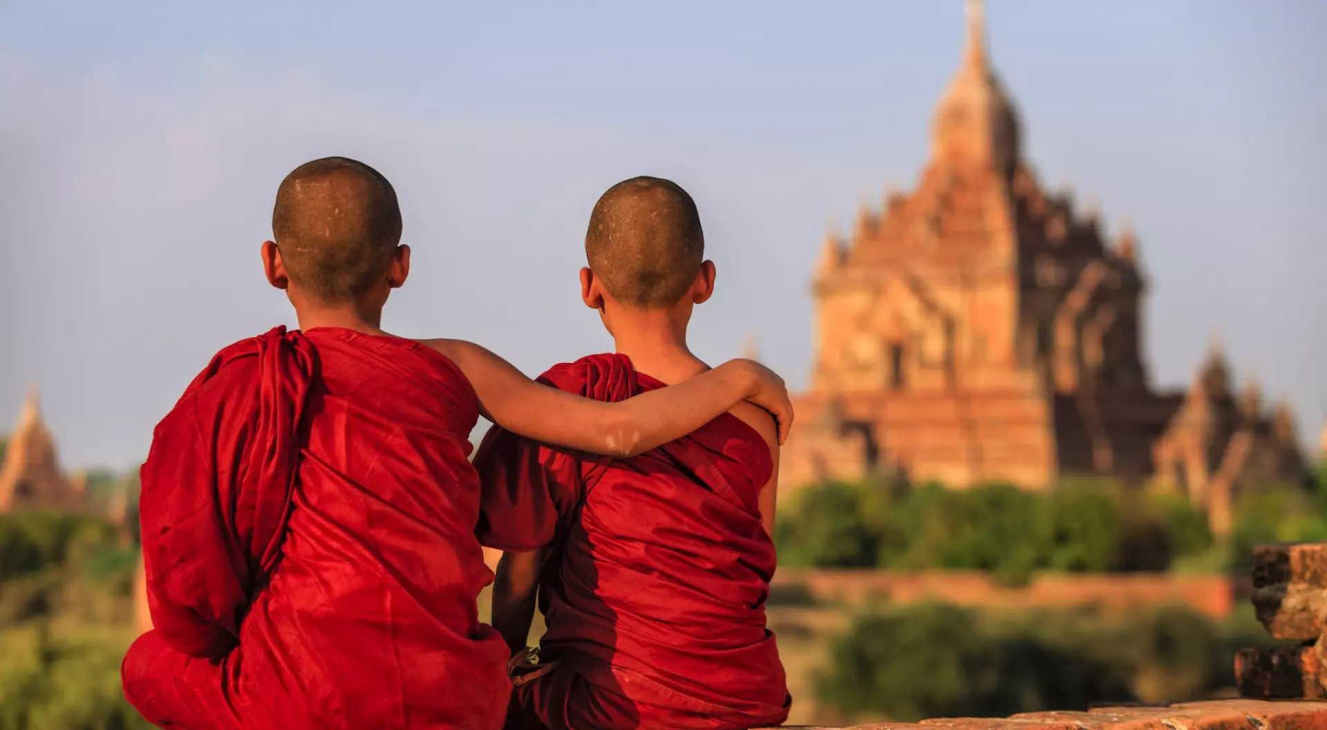 Young Buddhist monks sitting on the temple and looking at the view of ancient Bagan, Myanmar (Burma)