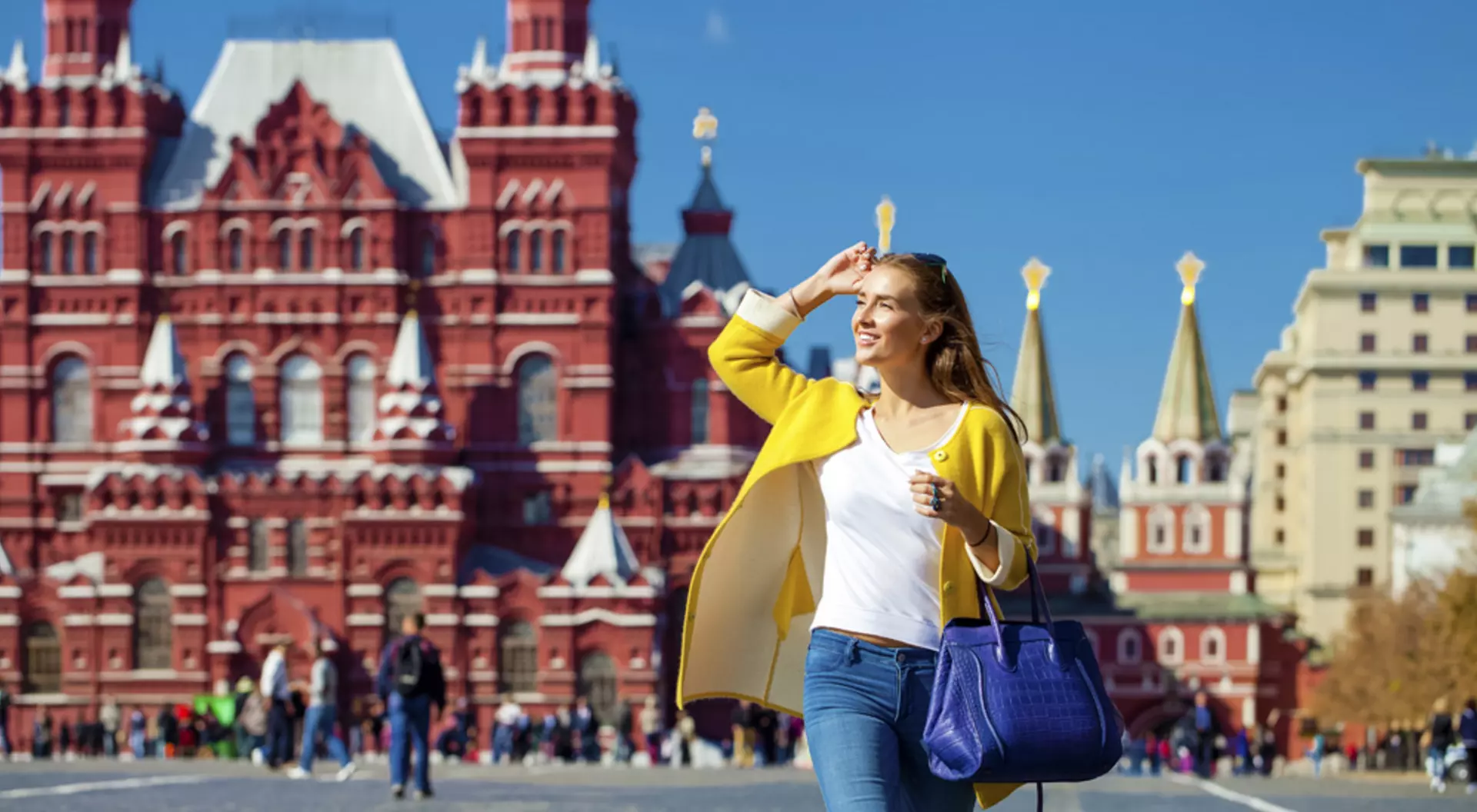 Moscow, Russia Young happy woman in yellow coat walking in Red Square in Moscow, Russia