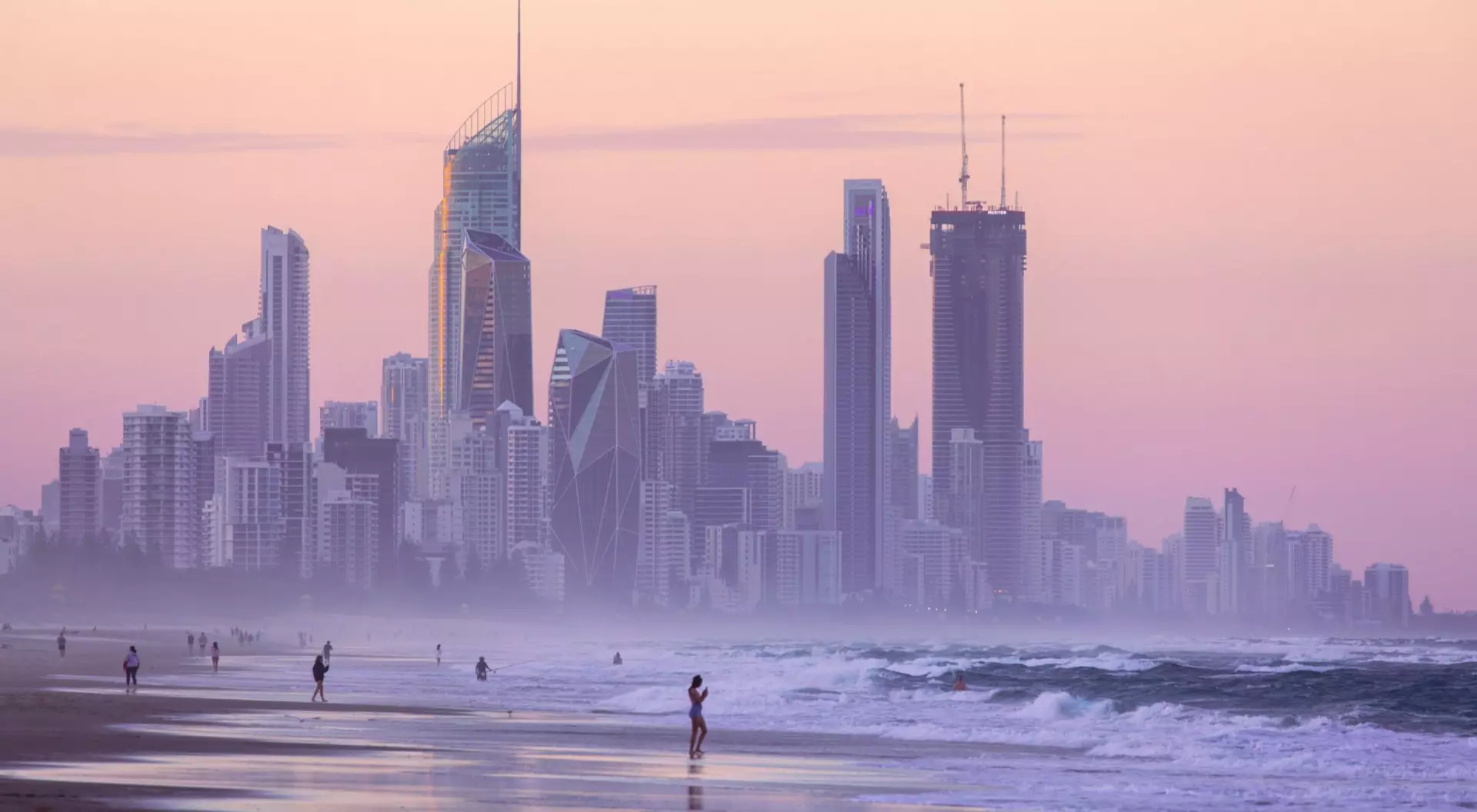 Gold Coast, Australia People walk along the beach at twilight against a backdrop of the Gold Coast skyscrapers in Australia.