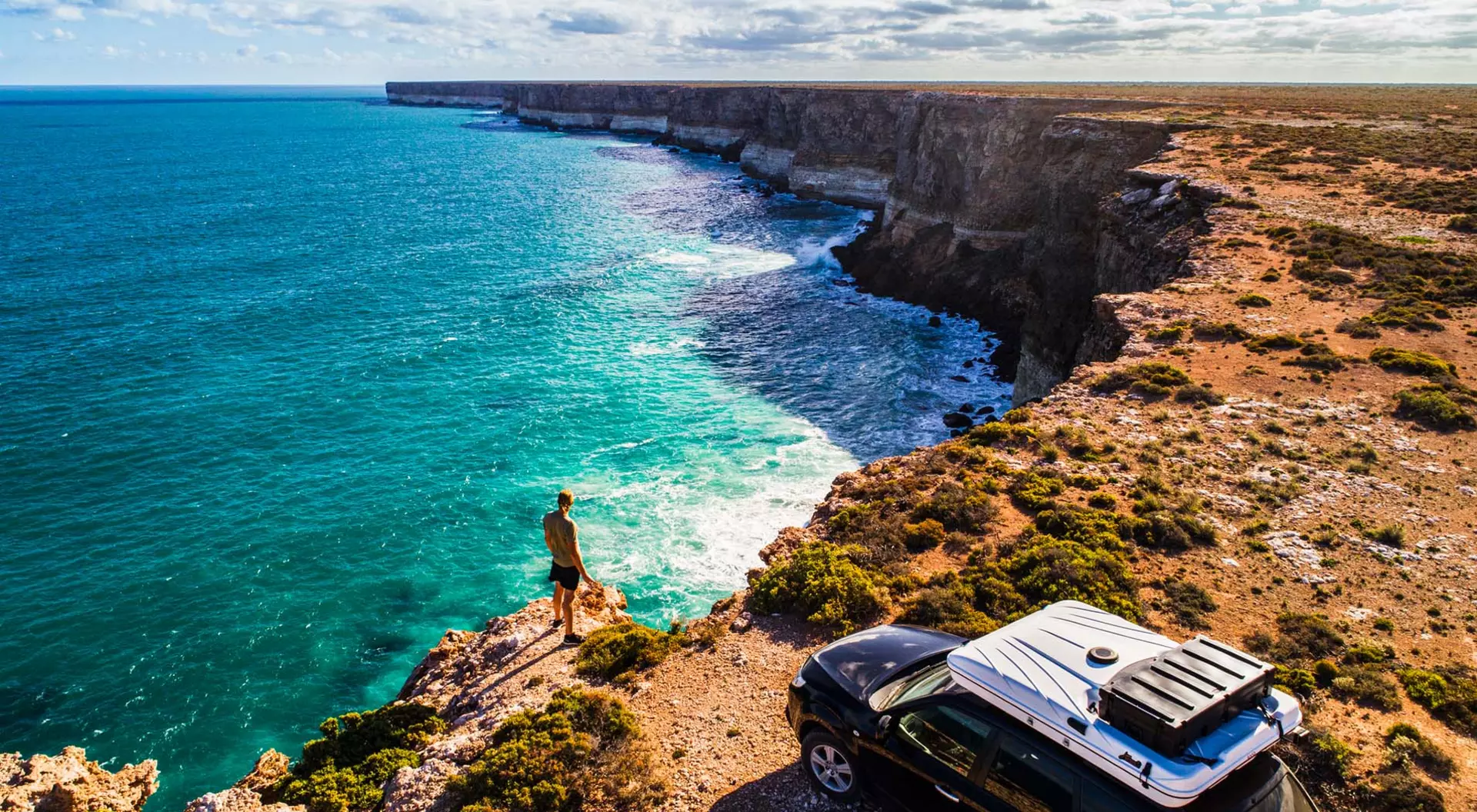 A man standing beside his car on the coastline along the Great Australian Bight of Australia
