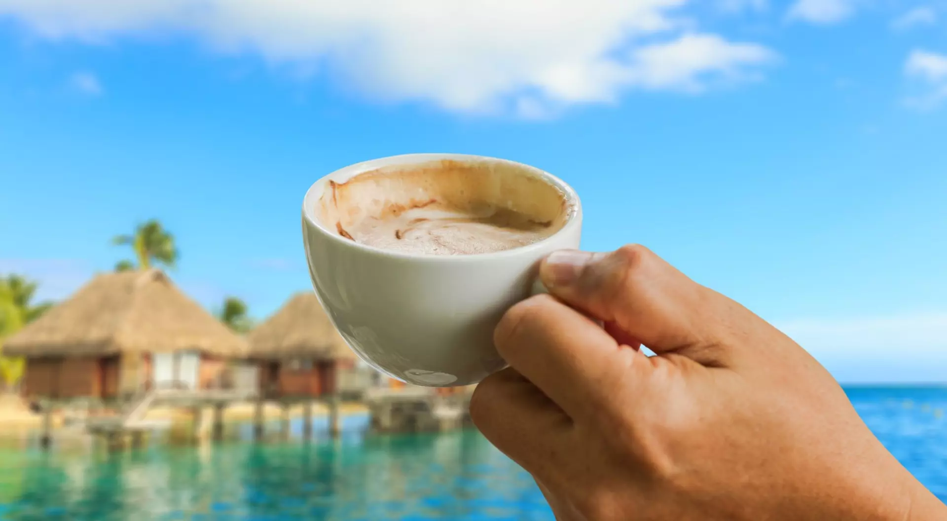 Tahiti, French Polynesia cup of coffee in the hands on seascape background