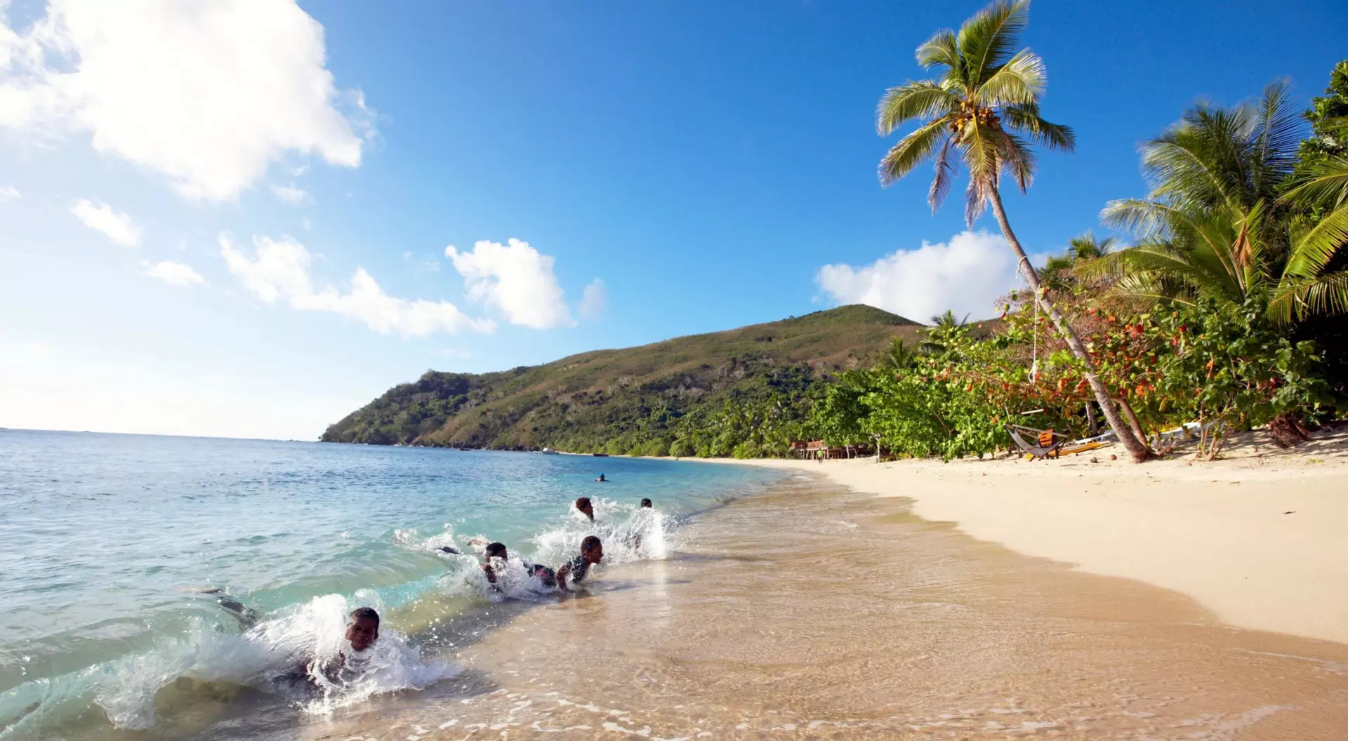 Botaira Resort, Fiji children playing in the surf on a white sand beach