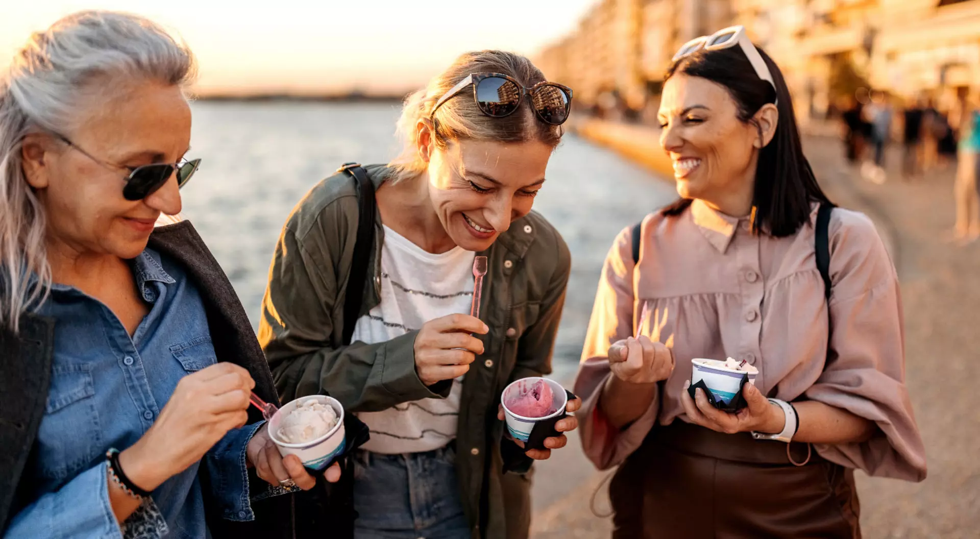 Three women enjoying ice cream on a beach in Greee.