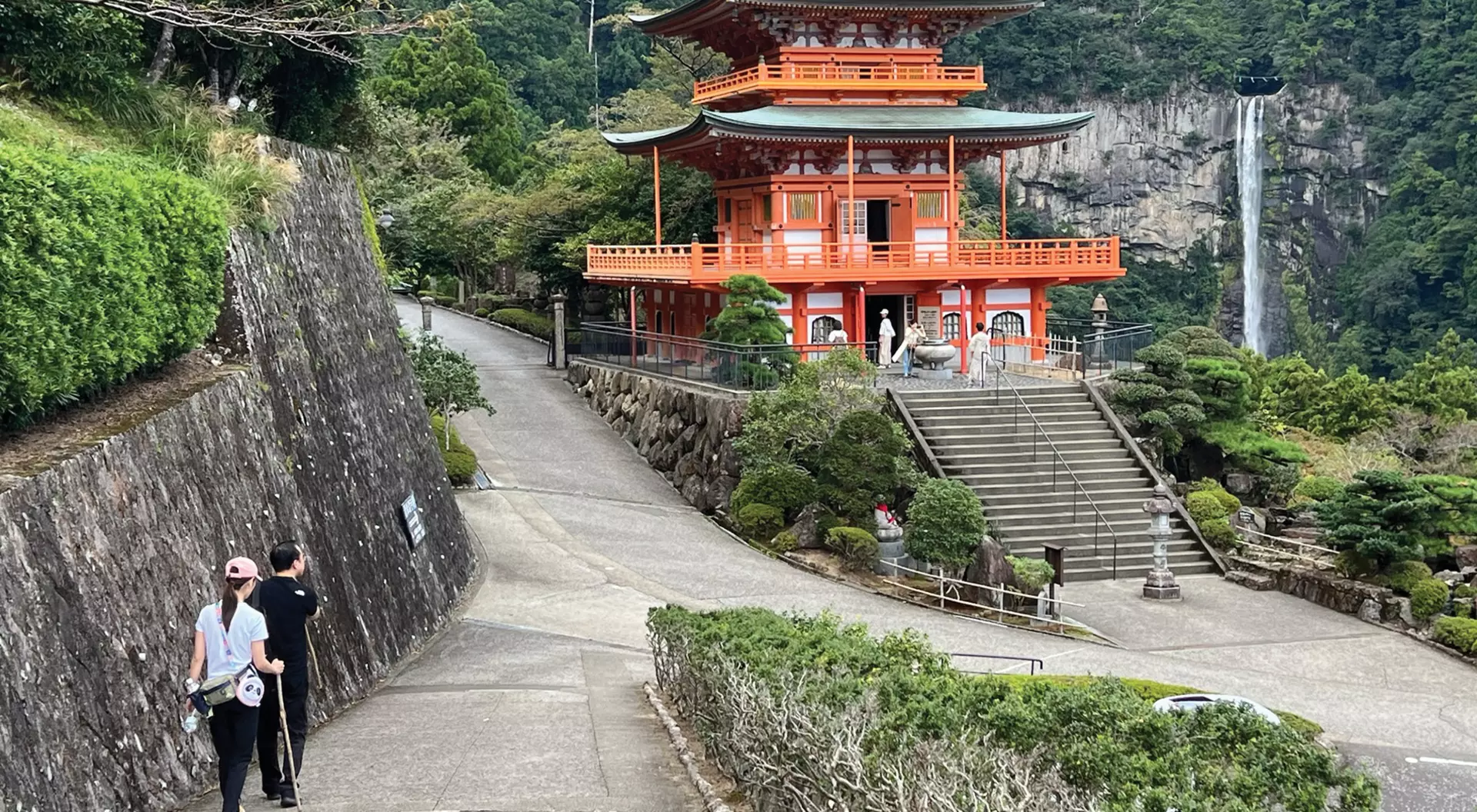 Japan hikers on a trail leading to a Japanese temple and waterfall