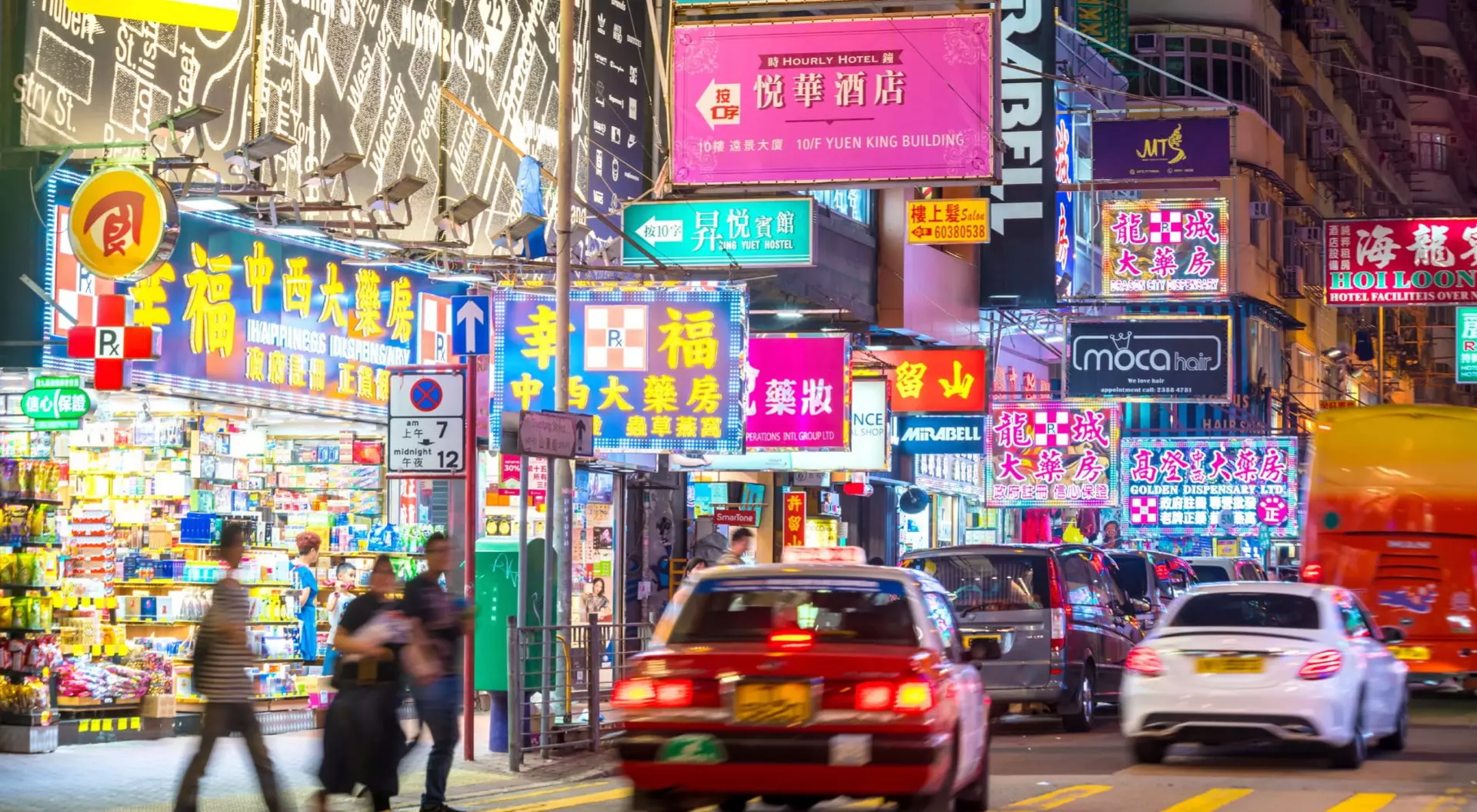 neon signs and cabs on a busy city street in East Asia