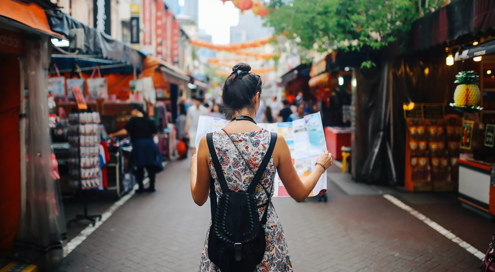 Young solo traveler woman in Singapore street market checking the map