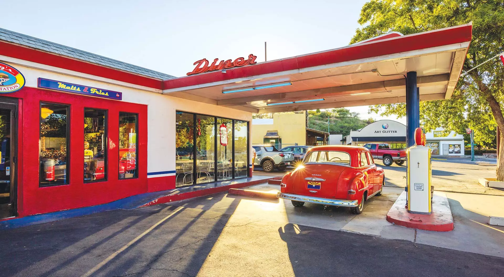 A vintage car at a gas station next to an old diner in middle America