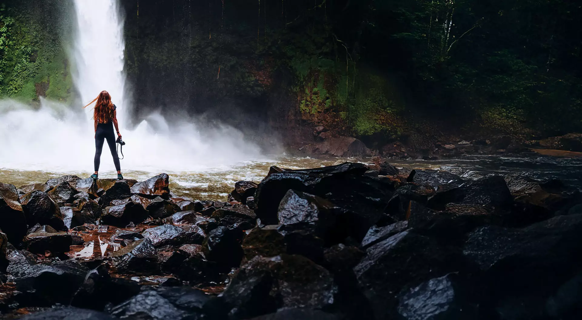 A woman with a camera at La Fortuna waterfall in Costa Rica