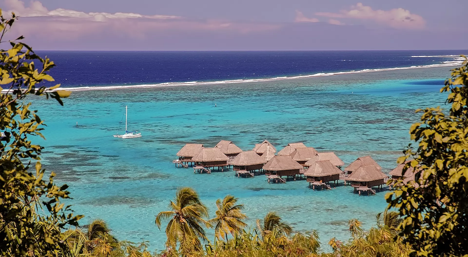 View of the coral reef surrounding a French Polynesia island, and the ocean of two colors: bungalows on the turquoise colored water of the shallow lagoon and blue color for the deep ocean.