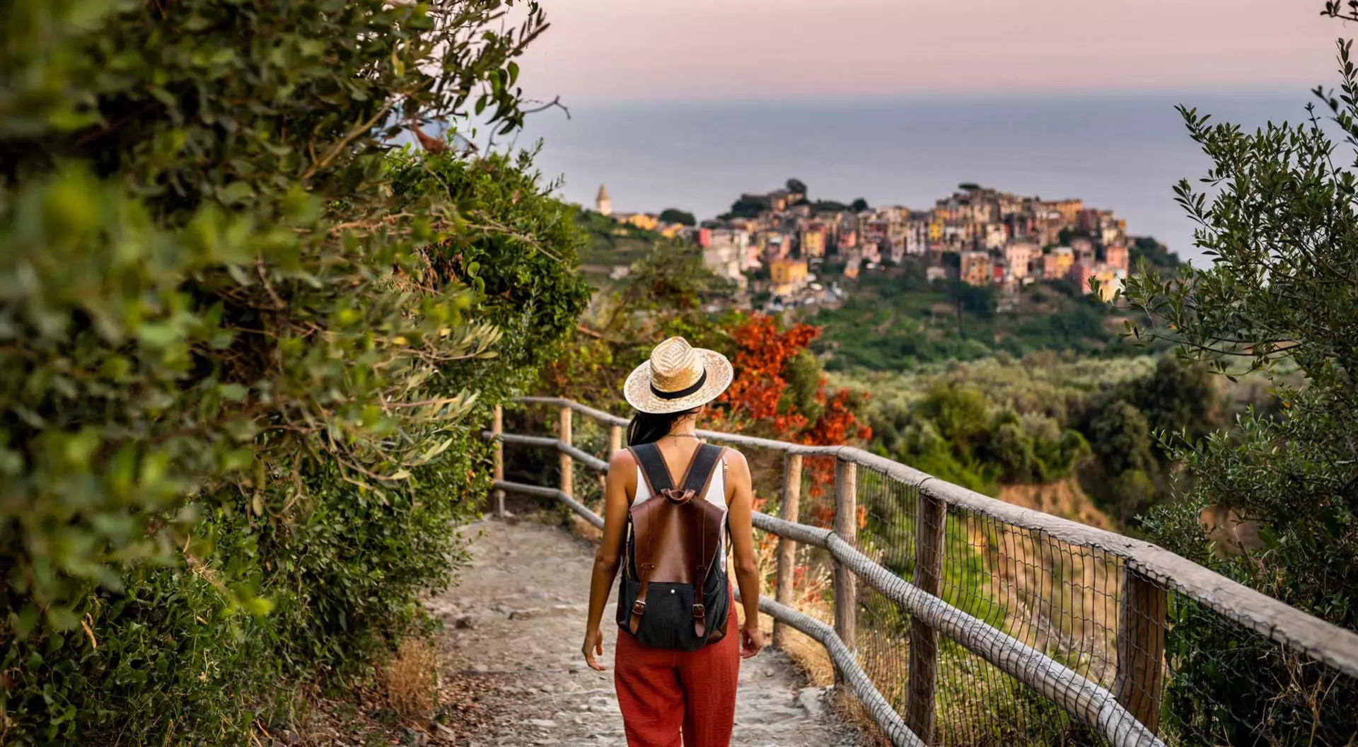 Corniglia, Italy A woman with a hat walks down a hillside path near the coastal village of Corniglia in the Cinque Terre in Italy
