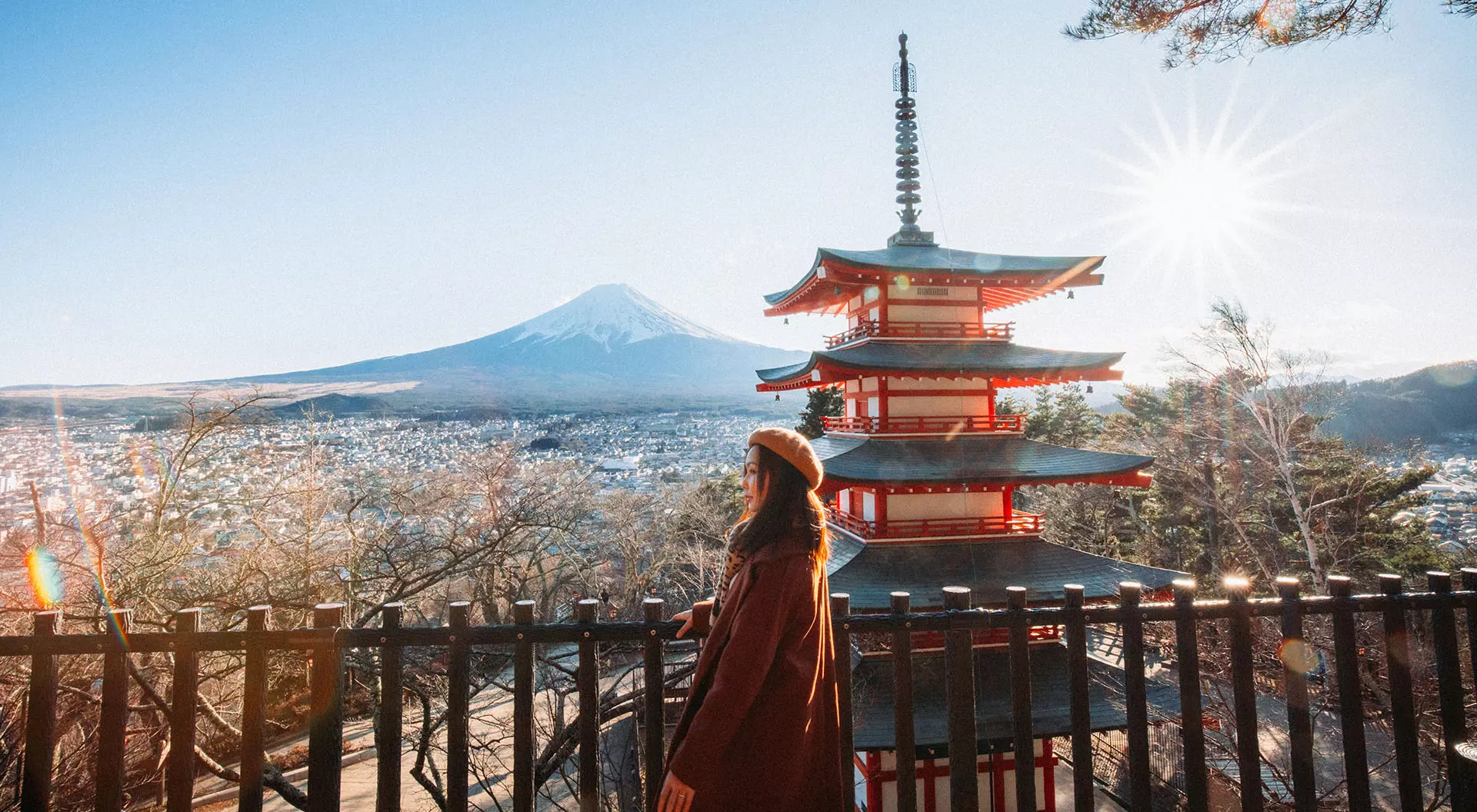A woman standing in front of Mount Fuji and a Japanese pagoda during the autumn season