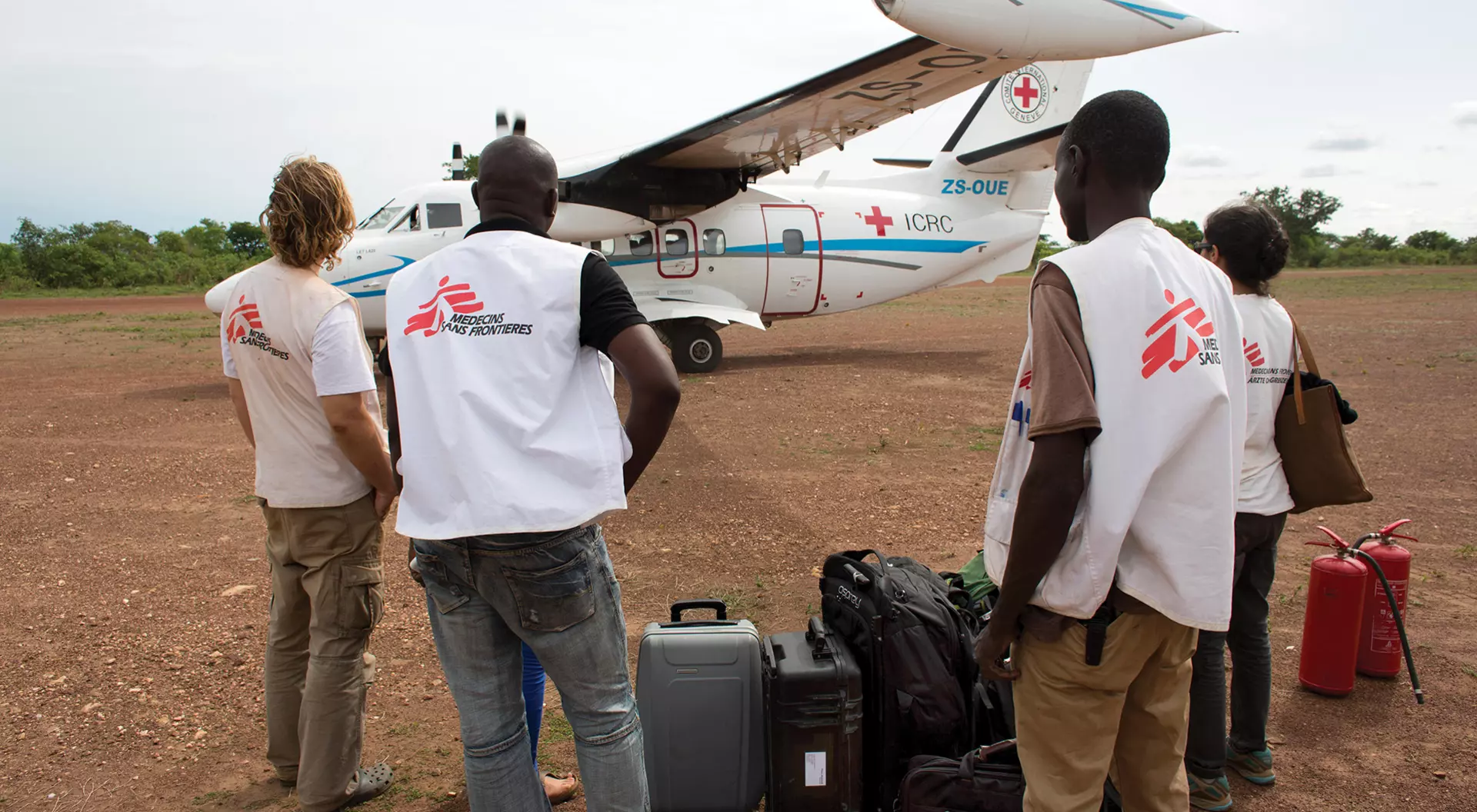 Doctors for MSF with luggage standing in front of a small plane