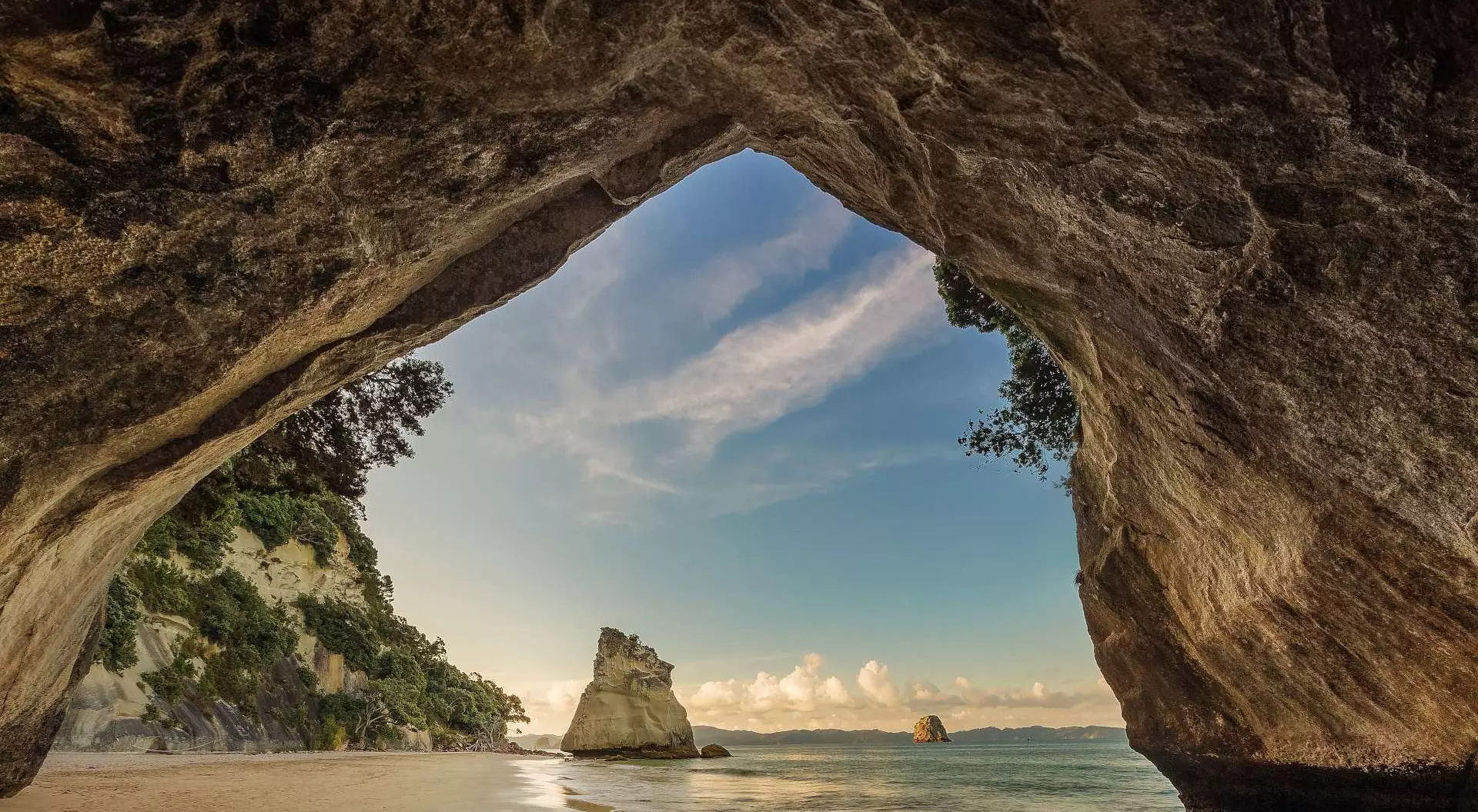 Cathedral Cove, New Zealand the triangular rock arch of Cathedral Cove gives way to the pristine sands of the bay with forest and ocean beyond
