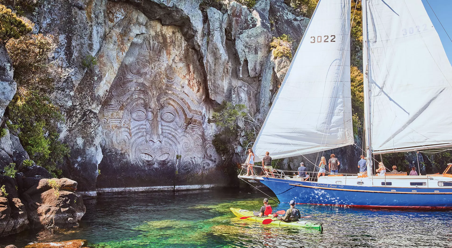 A kayak and sailboat in front of Maori carvings near Lake Taupo, New Zealand