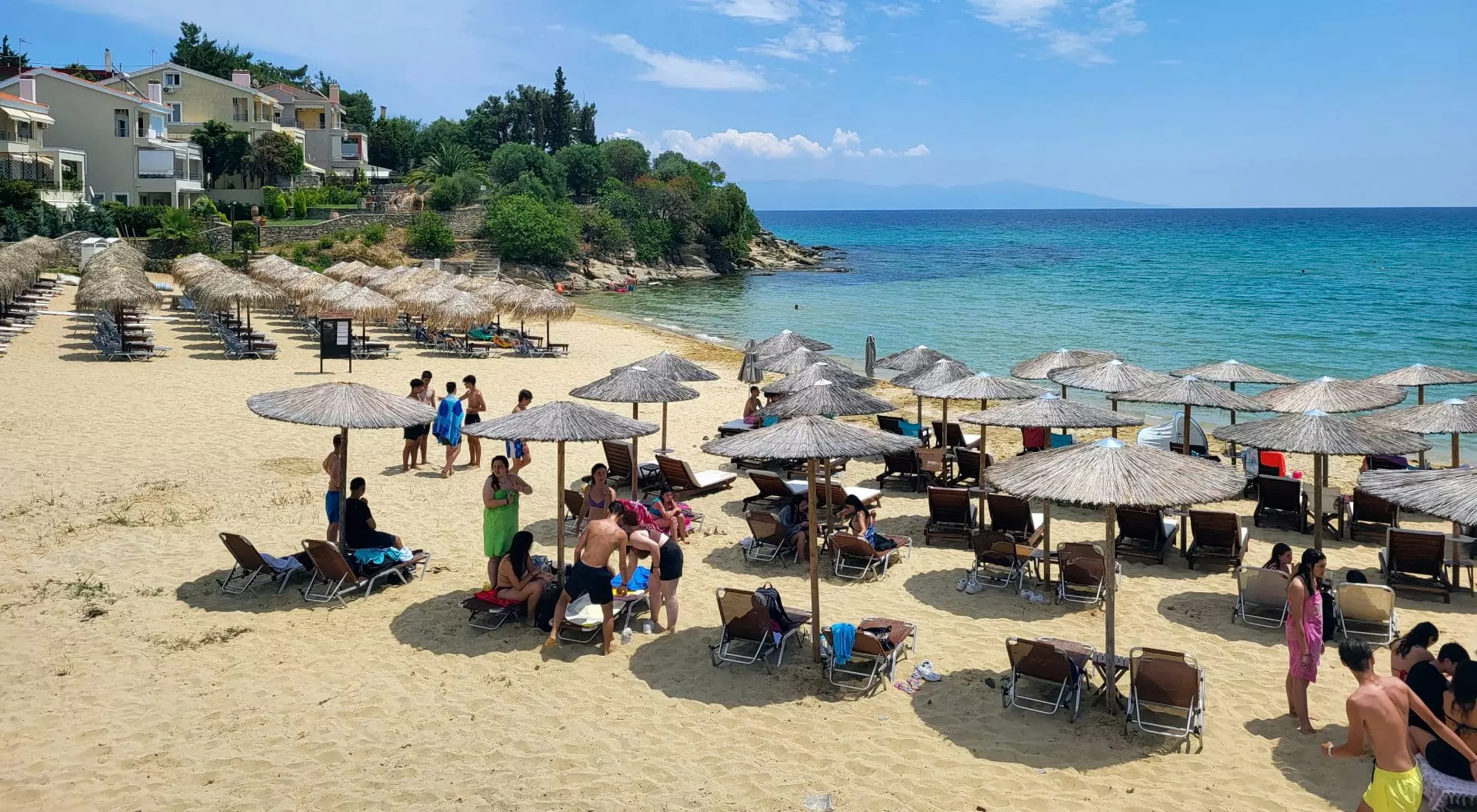 people enjoy a sunny sommer day on the sandy beach on Aegean sea