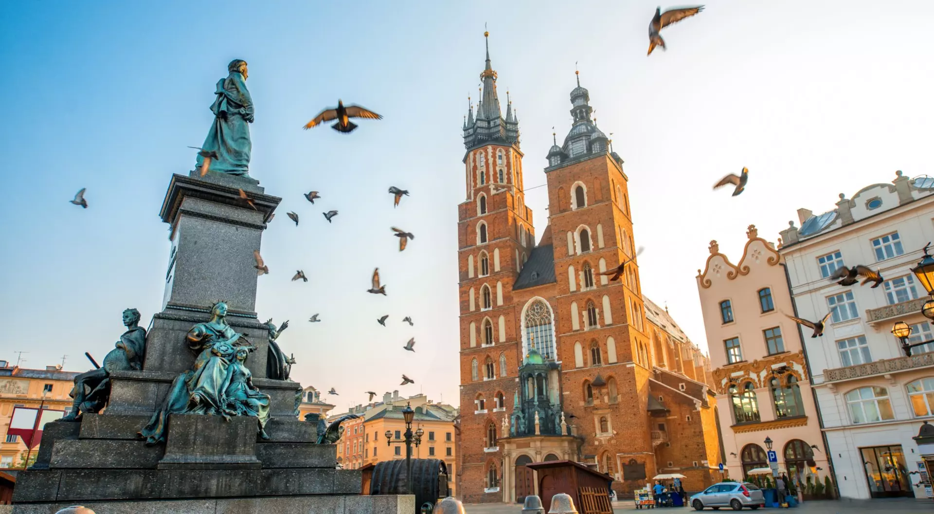 Krakow, Poland basilica and statue with pigeons in main square of old European city