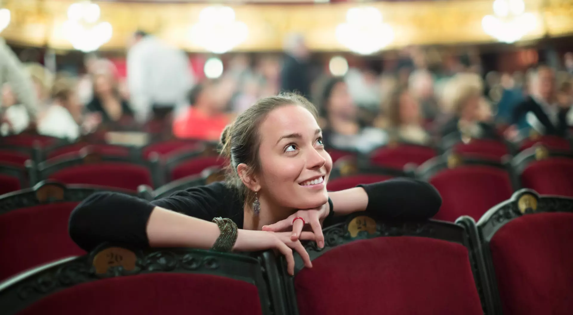 Smiling young woman sitting in auditorium of theatre