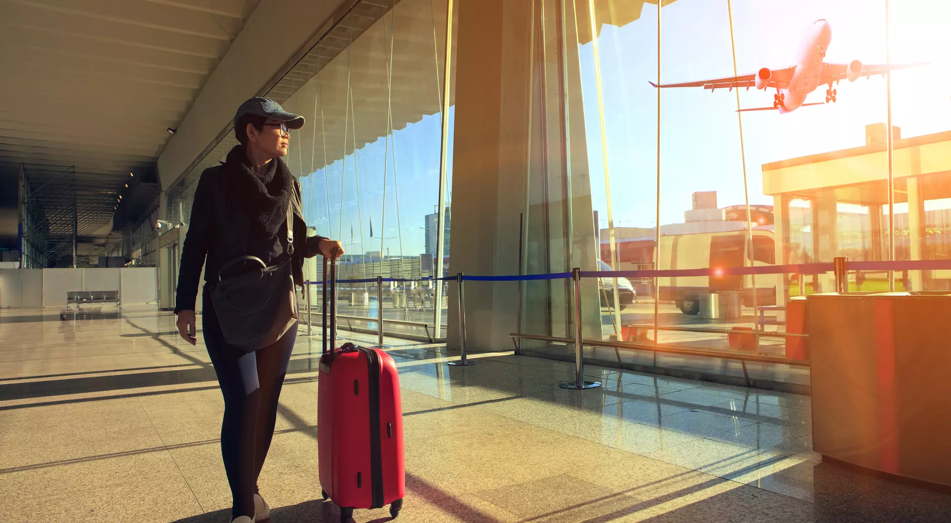Traveling woman and luggage walking in airport terminal and airplane flying outside