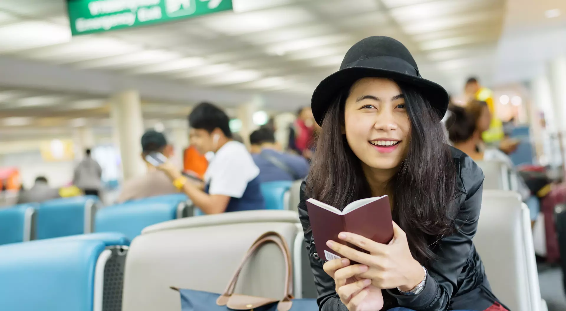 Young Asian woman solo traveller holding passport and waiting for flight travel at airport terminal