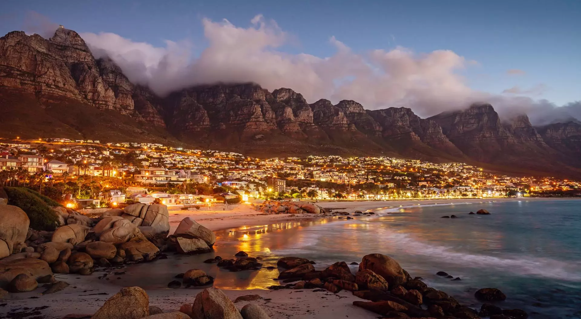 Cape Town Camps Bay outside Cape Town in South Africa at sunset, as the town lights up and the light fades.