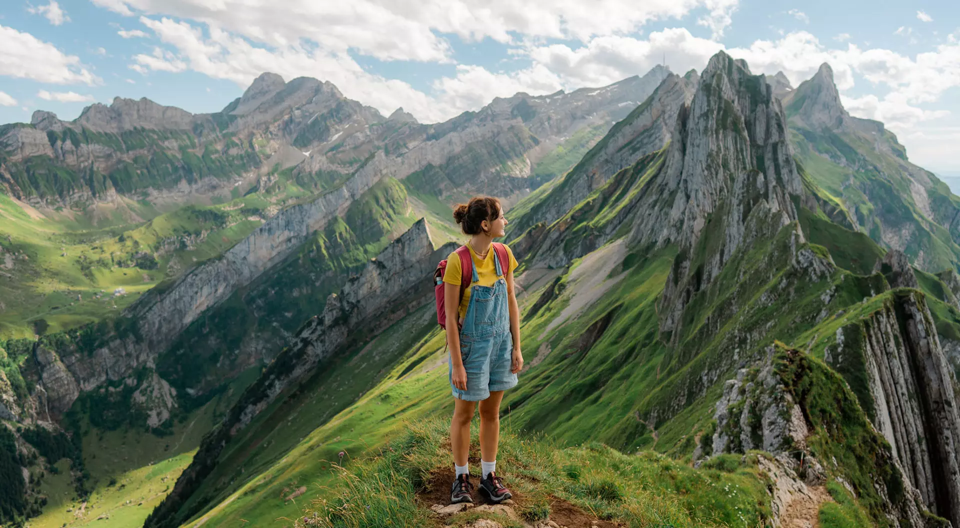 A woman standing on the top of a mountain looking out at vistas in Switzerland.