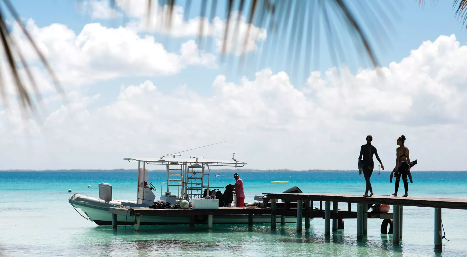 Tahiti, French Polynesia Two people with snorkeling gear boarding a docked motorboat
