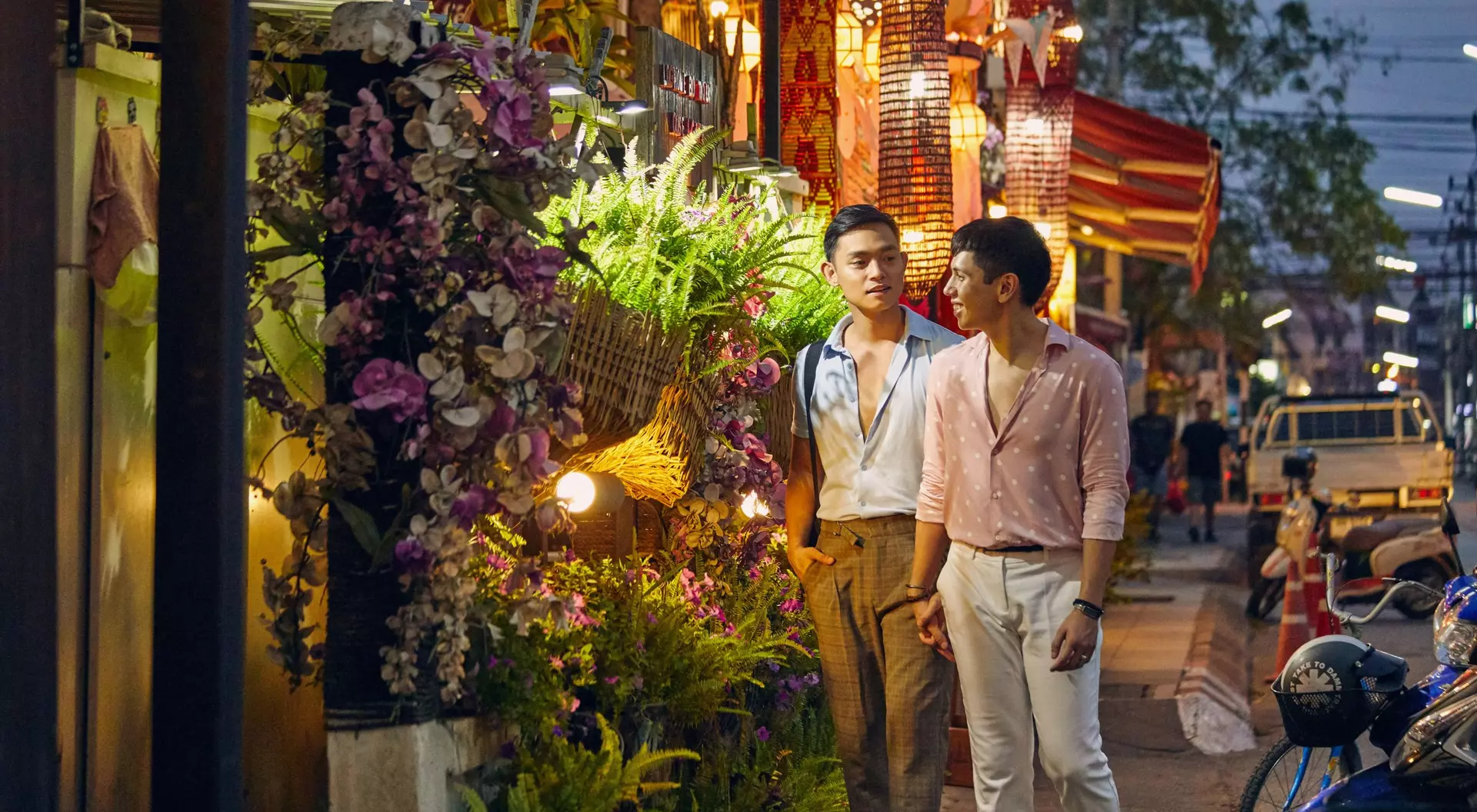 two men walking down a colourful street at night