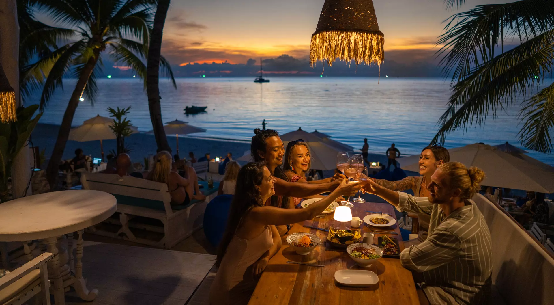 A group of people enjoy a meal at night in a seaside restaurant in Thailand.