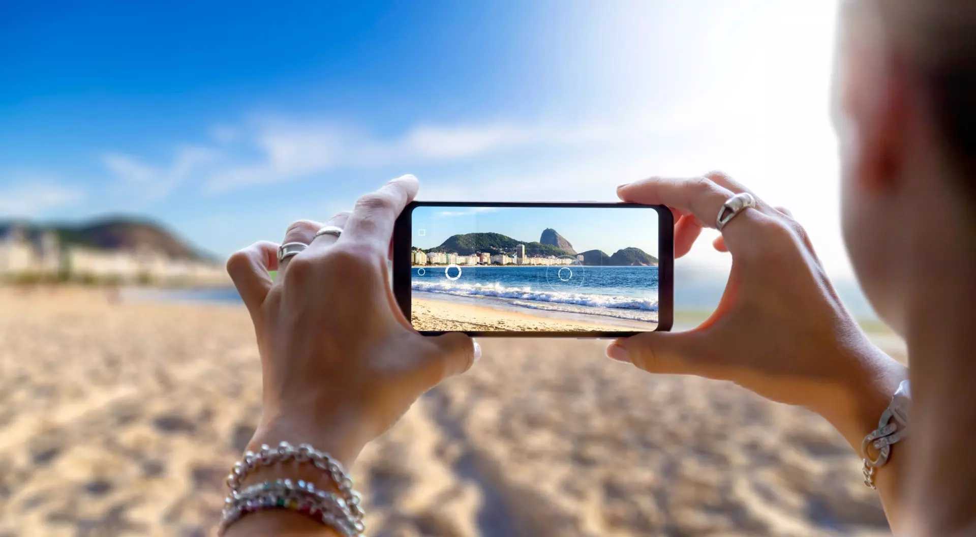 View of a beach and shoreline through the screen of smartphone from a person taking a photo.