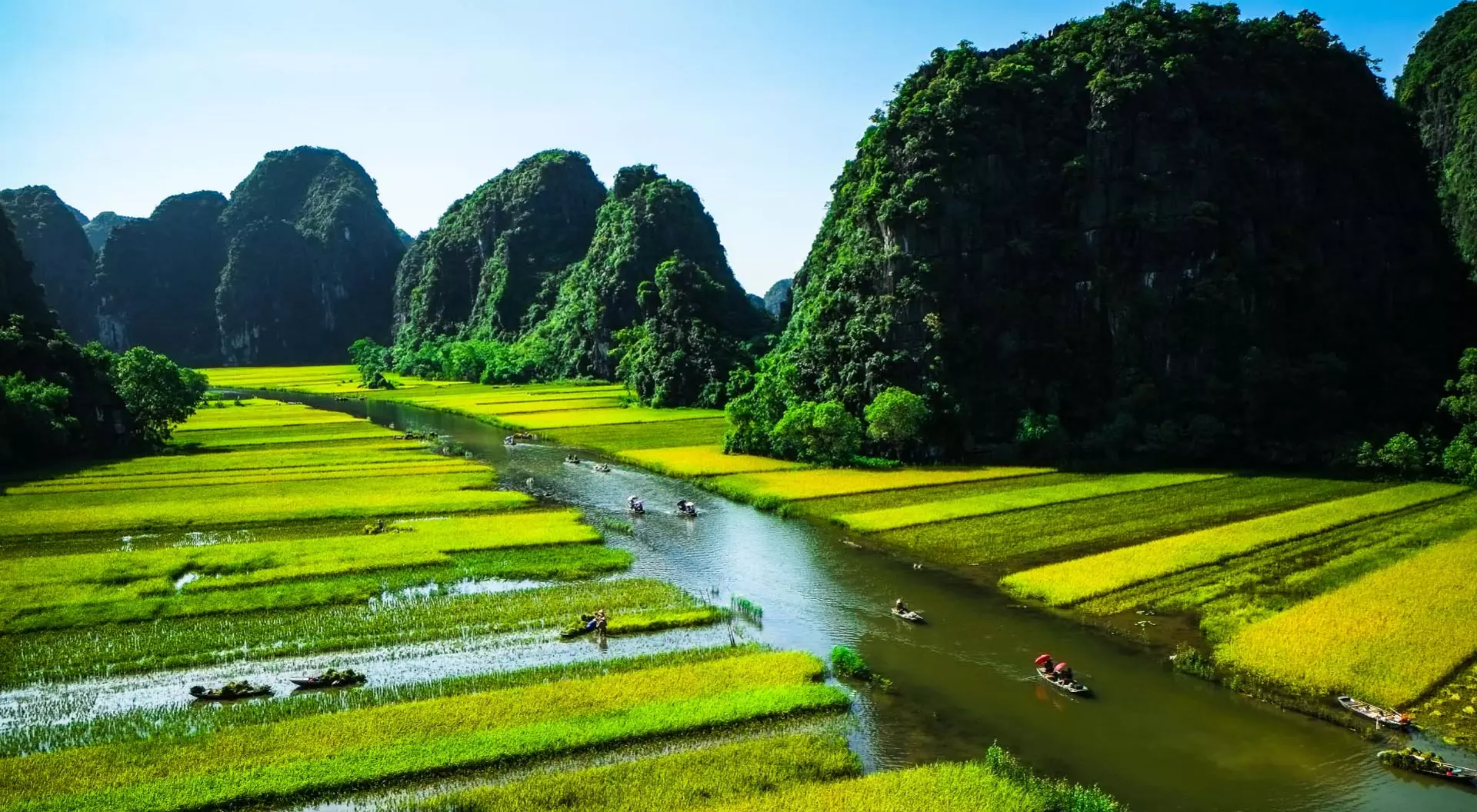 Ninh Binh is famous for its rice paddies amidst limestone mountains. Panoramic view of rice paddies, boats, rivers, and limestone mountains in Ninh Binh, Vietnam