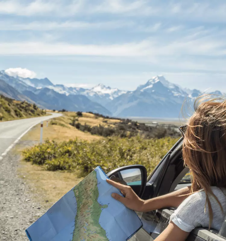 Woman in a car along a highway overlooking a beautiful view, checking a map for directions