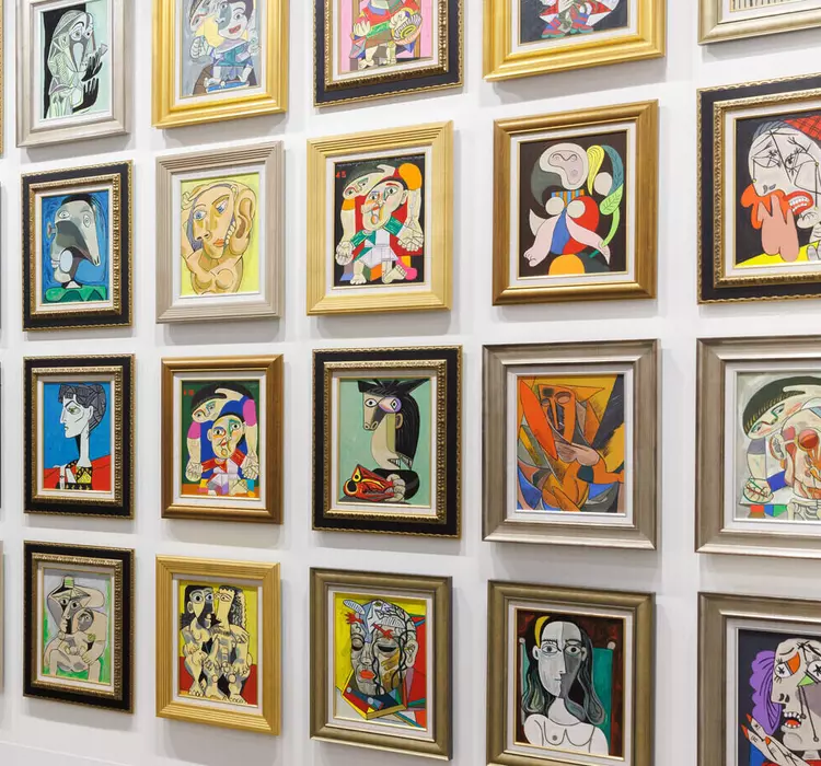 A woman observes a wall of colorful, framed abstract portraits in a modern art gallery.